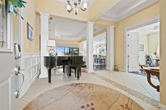 tiled foyer entrance featuring ornamental molding, a chandelier, and ornate columns