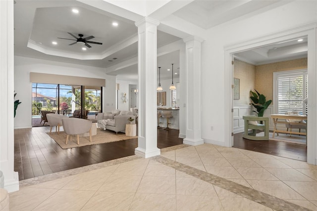 living room featuring a tray ceiling, decorative columns, recessed lighting, ornamental molding, and baseboards