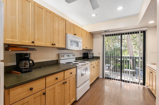 kitchen with white appliances, wood finished floors, light brown cabinets, ceiling fan, and dark countertops