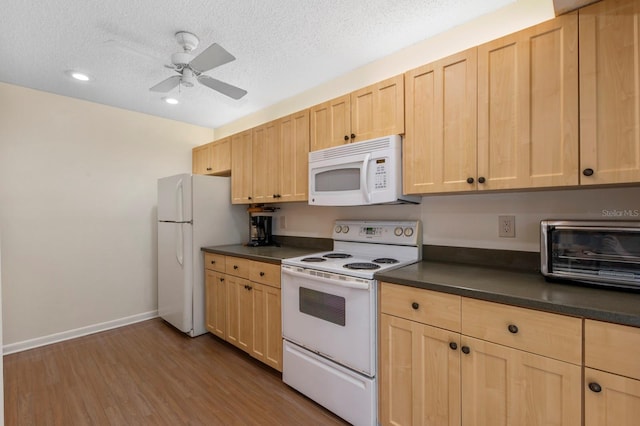 kitchen featuring white appliances, dark countertops, and light brown cabinets
