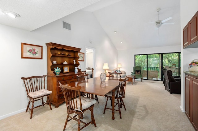 dining space featuring high vaulted ceiling, ceiling fan, light carpet, and a textured ceiling