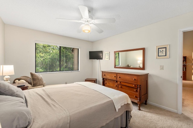 bedroom with light colored carpet, a textured ceiling, baseboards, and a ceiling fan