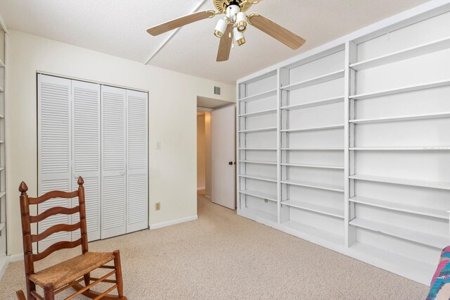 sitting room with a textured ceiling, light carpet, and ceiling fan