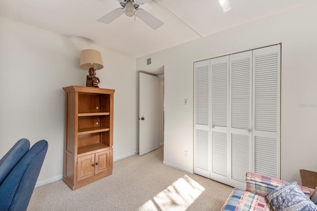 bedroom with light carpet, ceiling fan, baseboards, and a closet