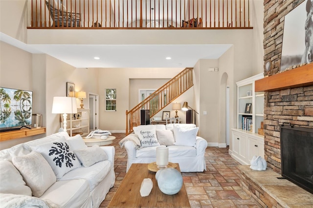 living room with a towering ceiling, built in features, and a fireplace