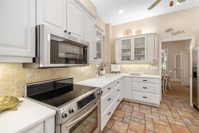 kitchen with decorative backsplash, white cabinets, stainless steel appliances, and ceiling fan