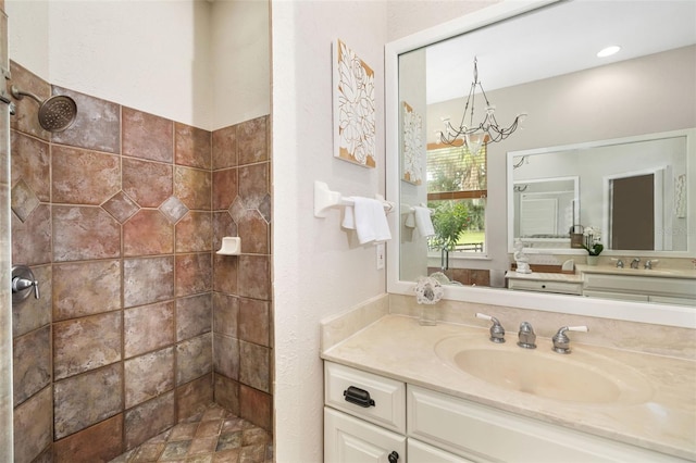 bathroom featuring vanity, a chandelier, and tiled shower