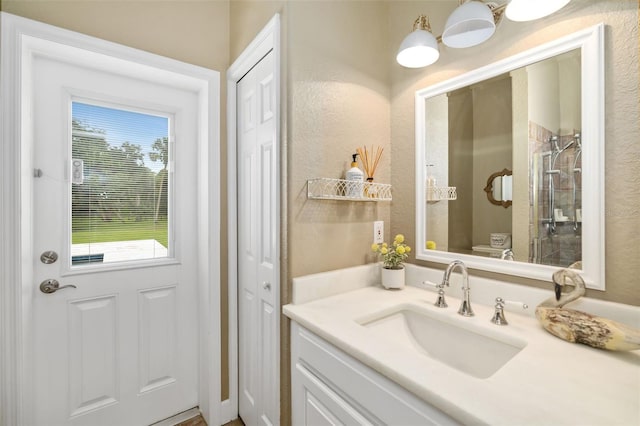 bathroom with vanity, a tile shower, and toilet