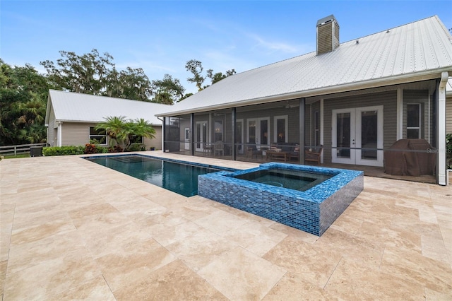 view of pool with french doors, a patio area, a sunroom, and an in ground hot tub