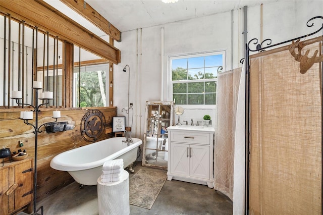 bathroom with vanity, a bathtub, concrete flooring, and plenty of natural light