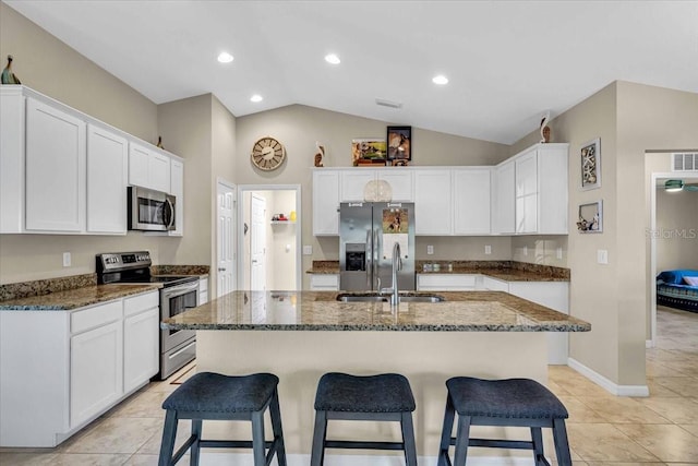 kitchen with an island with sink, appliances with stainless steel finishes, sink, and lofted ceiling