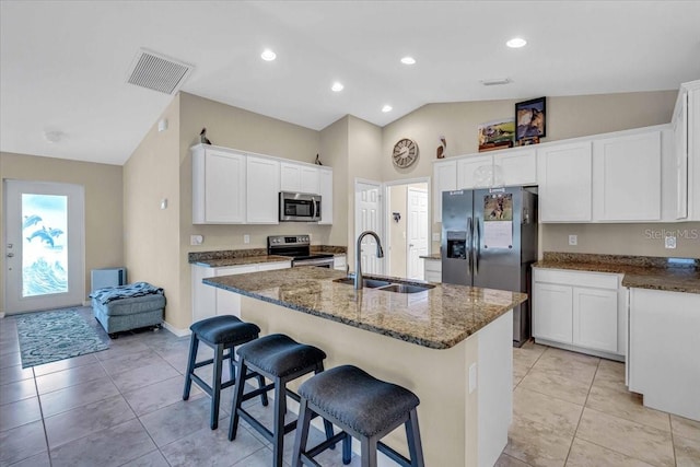 kitchen with white cabinetry, stainless steel appliances, lofted ceiling, a center island with sink, and sink