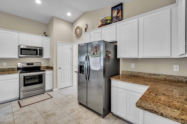 kitchen with appliances with stainless steel finishes, white cabinetry, and vaulted ceiling