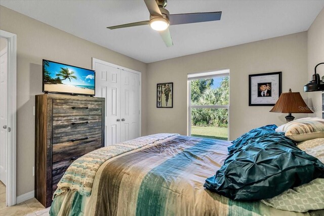 tiled bedroom with ceiling fan and a closet