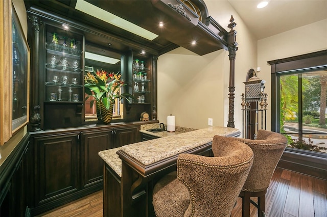 bar with light stone countertops, wood-type flooring, and lofted ceiling