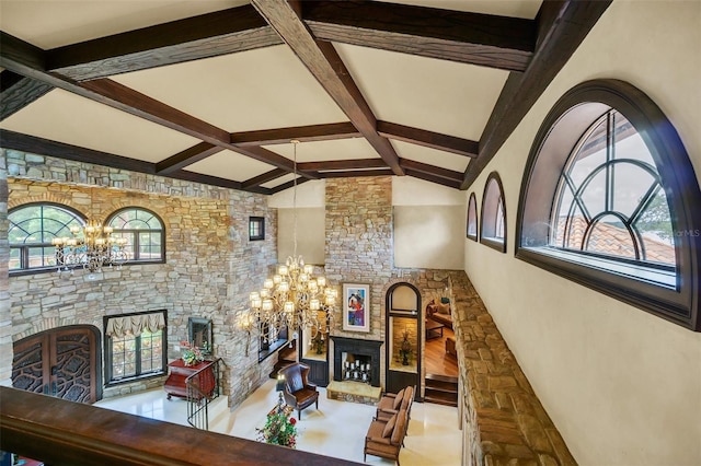 office area featuring vaulted ceiling with beams, a stone fireplace, and an inviting chandelier