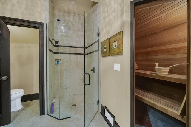 bathroom featuring a shower with door and toilet