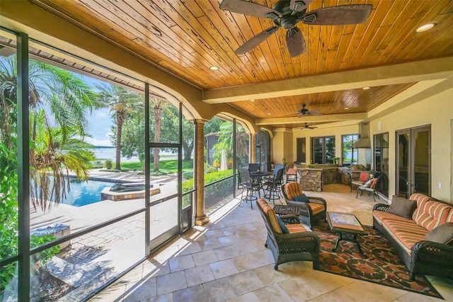 sunroom featuring wood ceiling, ceiling fan, and beamed ceiling