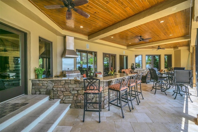 view of patio / terrace with exterior kitchen, ceiling fan, a bar, and grilling area