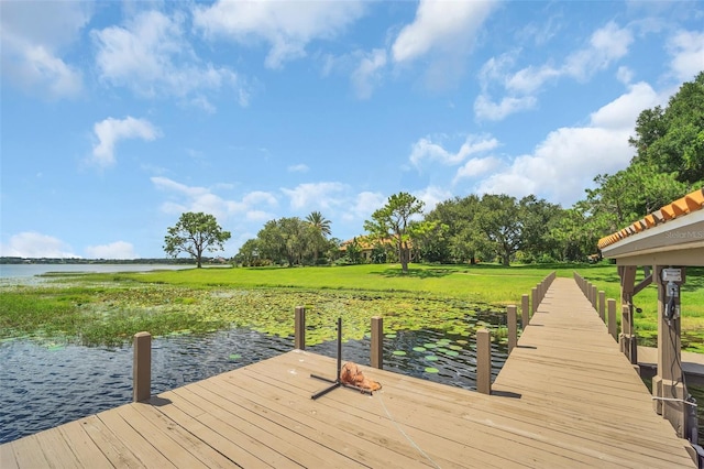 view of dock with a yard and a water view