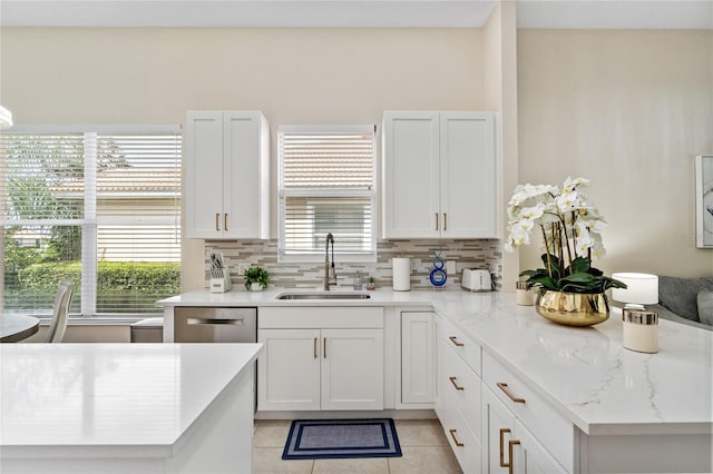 kitchen with white cabinetry, backsplash, sink, and light tile patterned floors