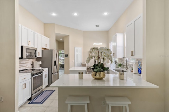 kitchen with stainless steel appliances, sink, kitchen peninsula, and white cabinets