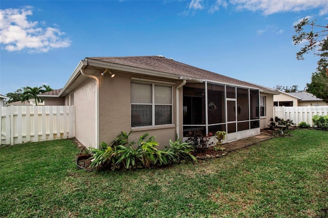 rear view of property featuring a sunroom and a yard