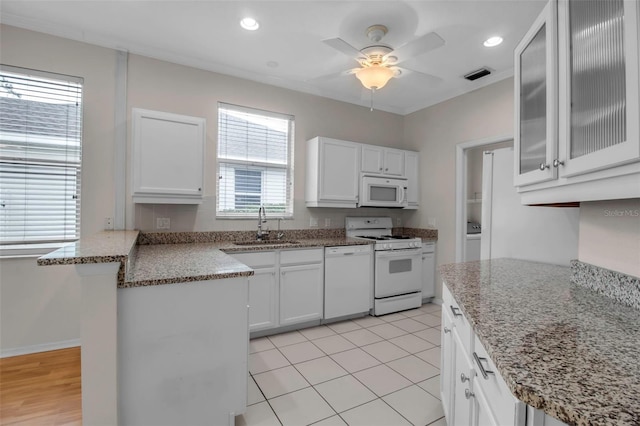 kitchen featuring light stone countertops, white appliances, sink, white cabinetry, and light tile patterned flooring