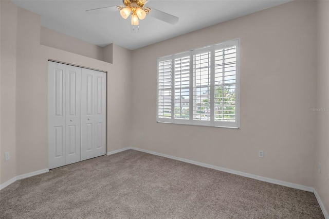 unfurnished bedroom featuring ceiling fan, light colored carpet, and a closet