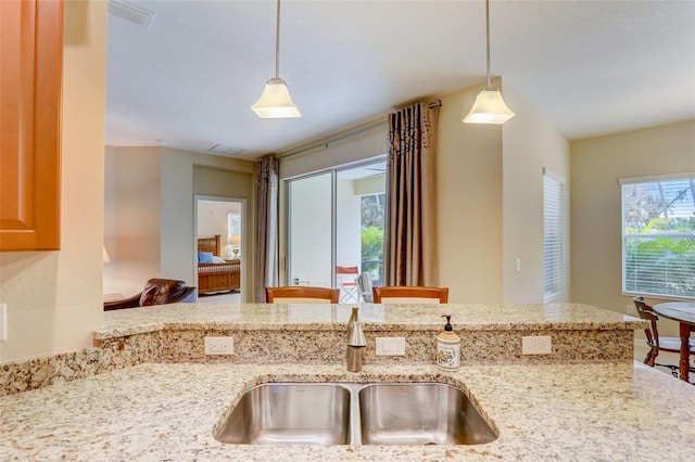 kitchen with sink, a wealth of natural light, and light stone counters