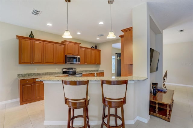 kitchen featuring decorative light fixtures, appliances with stainless steel finishes, kitchen peninsula, and a breakfast bar