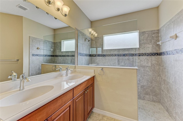 bathroom featuring tile patterned floors, a tile shower, and vanity