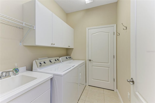 laundry area featuring sink, light tile patterned floors, a textured ceiling, cabinets, and separate washer and dryer