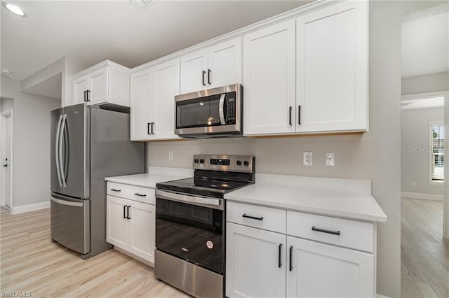 kitchen with light hardwood / wood-style flooring, appliances with stainless steel finishes, and white cabinets