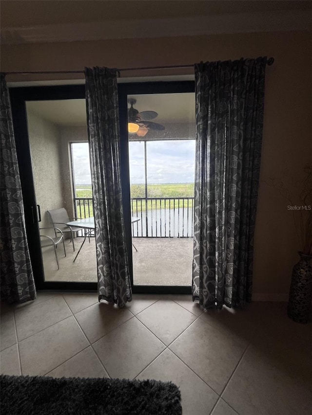 doorway to outside with a water view, tile patterned flooring, and ceiling fan