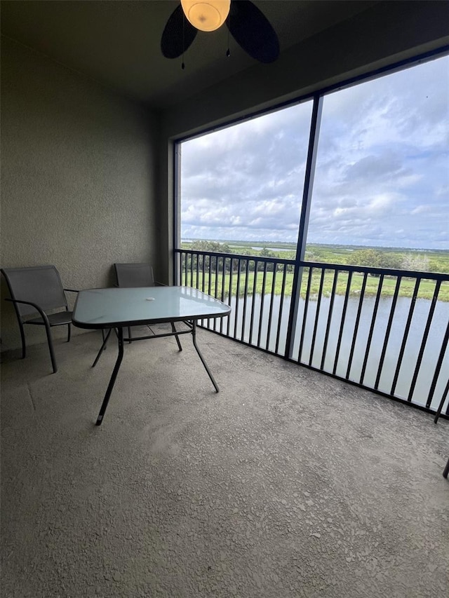 unfurnished sunroom with a water view and ceiling fan