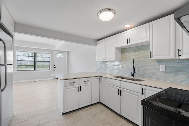 kitchen with stainless steel fridge, sink, kitchen peninsula, tasteful backsplash, and white cabinetry