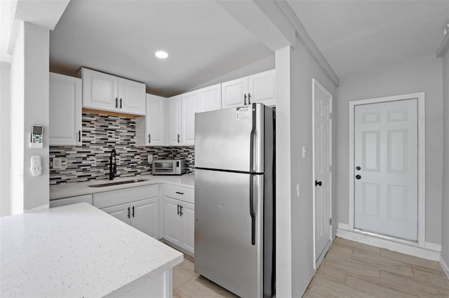 kitchen featuring lofted ceiling, stainless steel fridge, sink, and white cabinetry