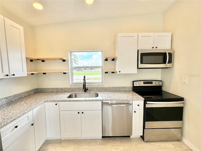 kitchen featuring white cabinetry, light stone counters, stainless steel appliances, and sink