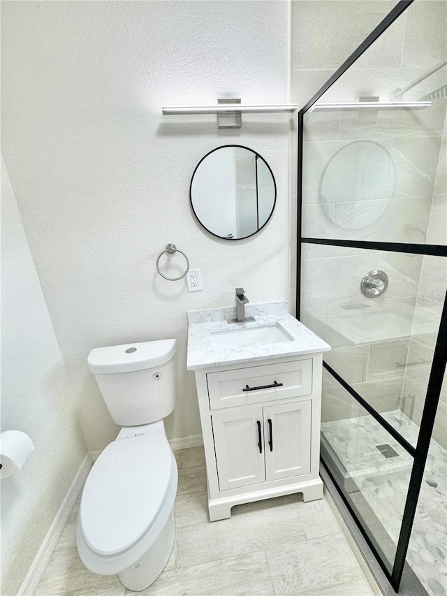 bathroom featuring a shower with door, vanity, and toilet