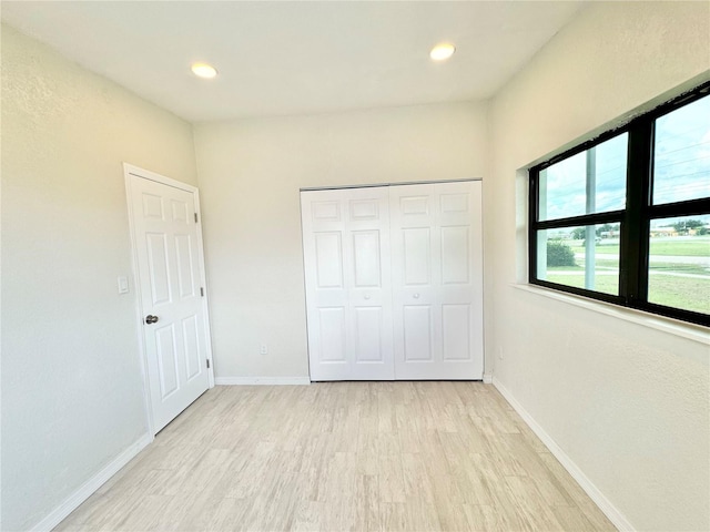 unfurnished bedroom with a closet and light wood-type flooring