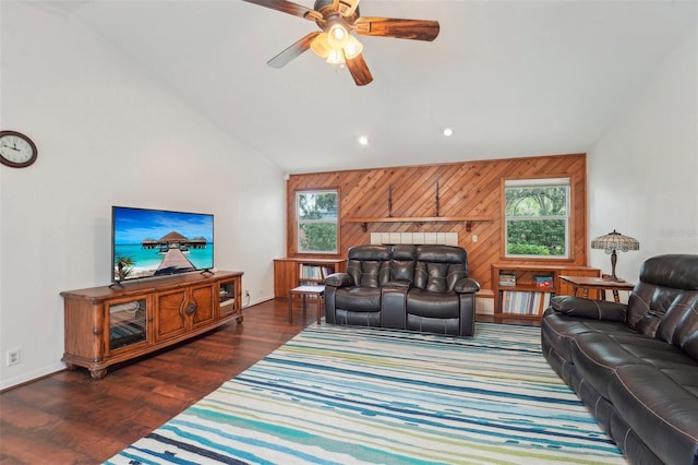 living room with wooden walls, lofted ceiling, ceiling fan, and dark wood-type flooring