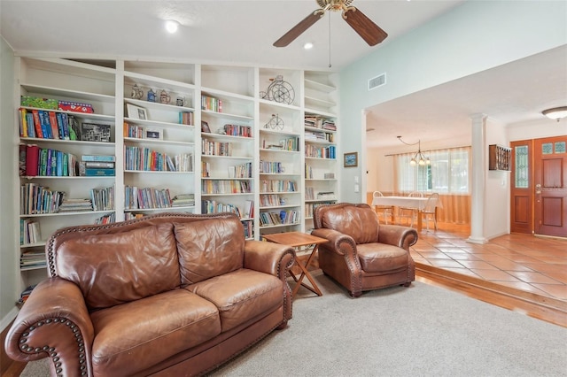 living room with ceiling fan with notable chandelier, decorative columns, and light tile patterned floors