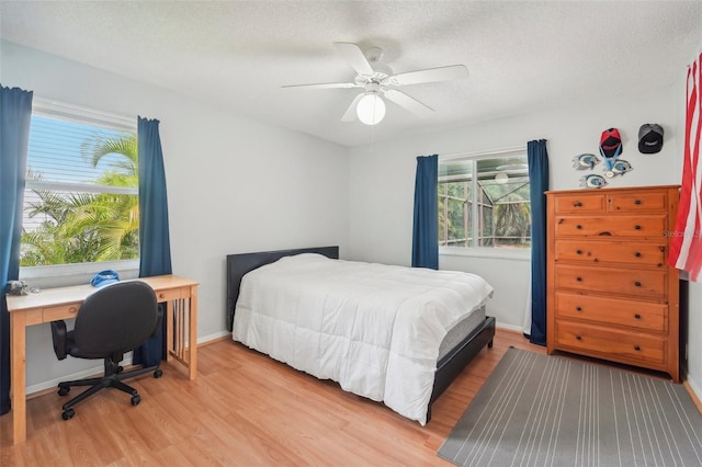 bedroom with light wood-type flooring, ceiling fan, and a textured ceiling