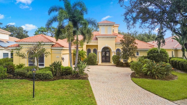 mediterranean / spanish-style house with a garage and a front lawn