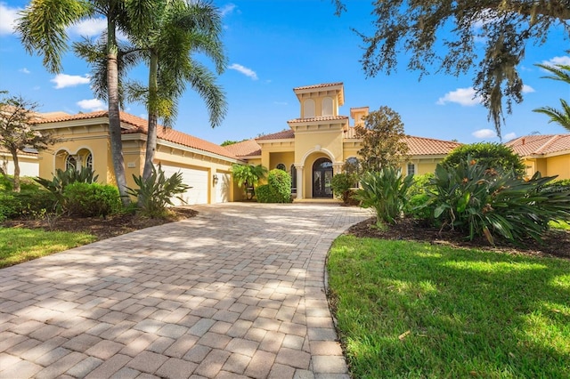 mediterranean / spanish home featuring a garage and a front yard