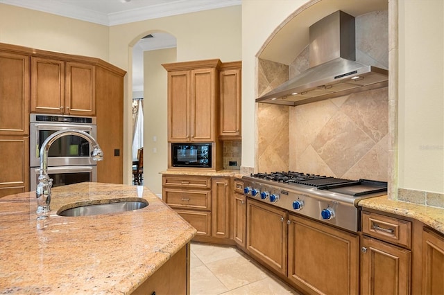 kitchen featuring light stone counters, ornamental molding, appliances with stainless steel finishes, decorative backsplash, and wall chimney range hood