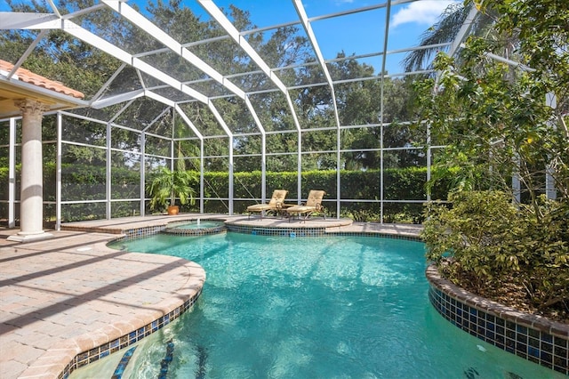 view of pool featuring a patio, glass enclosure, and an in ground hot tub