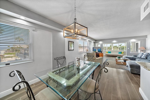 dining area featuring a notable chandelier, a textured ceiling, and hardwood / wood-style flooring