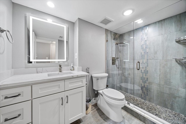 bathroom featuring a shower with shower door, vanity, and toilet